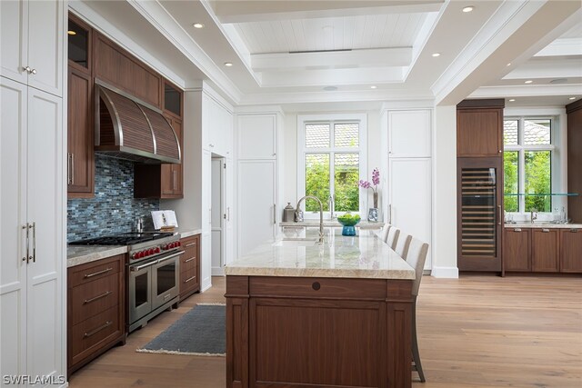 kitchen with wine cooler, a raised ceiling, a sink, double oven range, and premium range hood