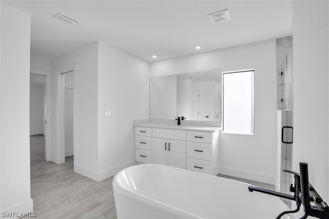 bathroom featuring hardwood / wood-style flooring, vanity, and plus walk in shower