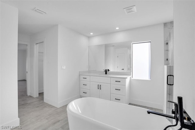 full bath featuring vanity, wood finished floors, visible vents, a freestanding bath, and a shower stall