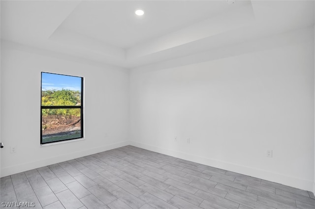 empty room with a tray ceiling and light hardwood / wood-style floors