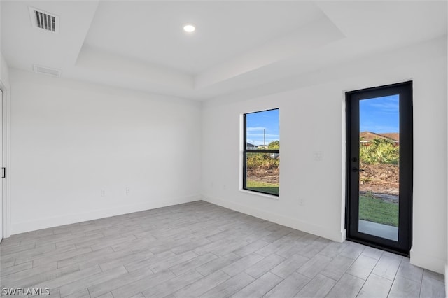 unfurnished room with a raised ceiling and light wood-type flooring