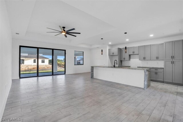 kitchen featuring light hardwood / wood-style floors, gray cabinets, and a kitchen island with sink