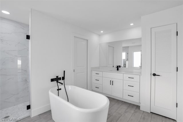 bathroom with hardwood / wood-style floors, vanity, and independent shower and bath