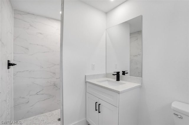 full bathroom with a marble finish shower, toilet, and vanity