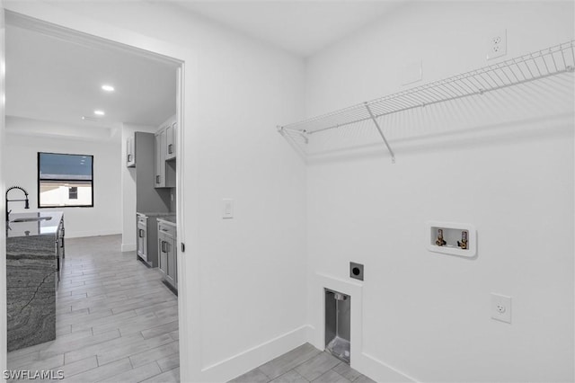 clothes washing area with electric dryer hookup, washer hookup, a sink, laundry area, and wood tiled floor