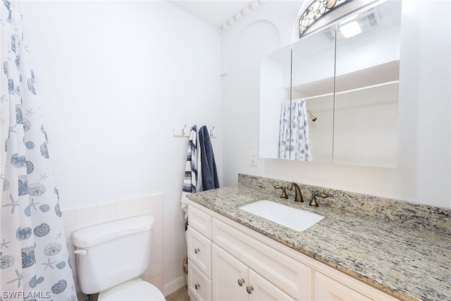 bathroom featuring tile walls, large vanity, and toilet