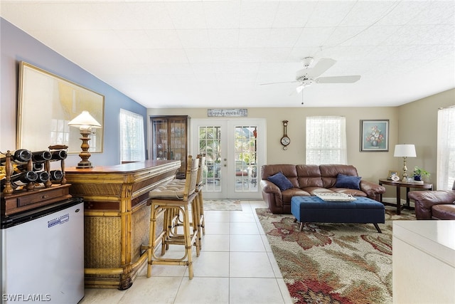 tiled living room with french doors and ceiling fan