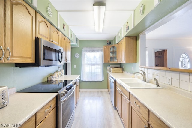 kitchen with tasteful backsplash, appliances with stainless steel finishes, light hardwood / wood-style floors, and sink