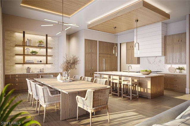 dining space featuring a tray ceiling, sink, and light wood-type flooring