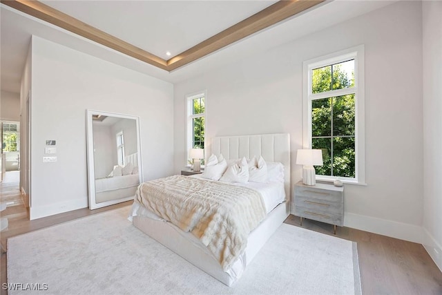 bedroom with light wood-type flooring, multiple windows, and baseboards