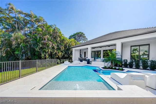 view of swimming pool featuring a patio area, fence, and a pool with connected hot tub