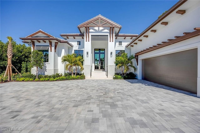 view of front facade with a garage, decorative driveway, and stucco siding