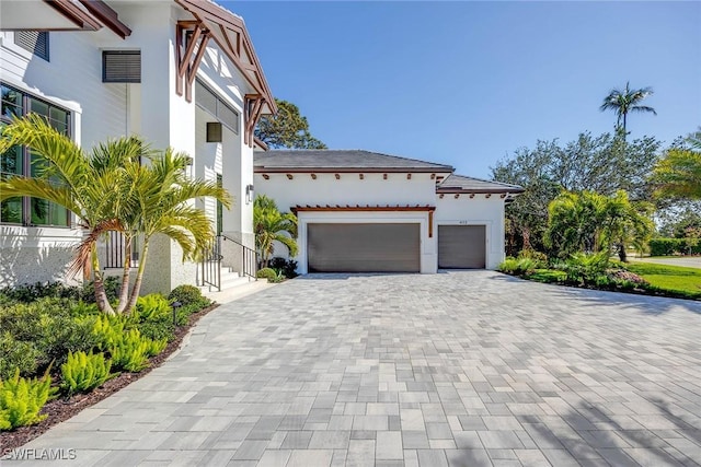 mediterranean / spanish house with an attached garage, decorative driveway, and stucco siding