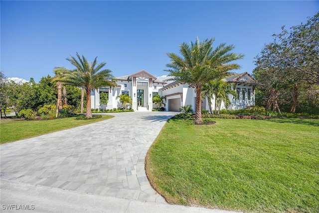 mediterranean / spanish house with an attached garage, decorative driveway, and a front yard