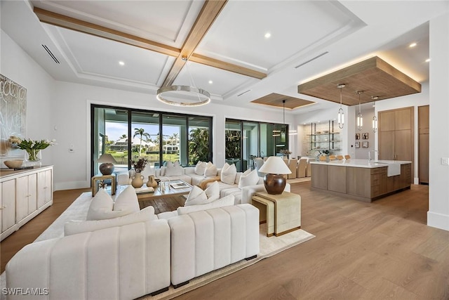 living area with coffered ceiling, light wood-style flooring, and baseboards