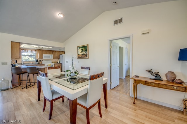 dining space featuring high vaulted ceiling and light wood-type flooring