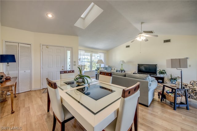 dining area featuring light hardwood / wood-style flooring, lofted ceiling with skylight, and ceiling fan