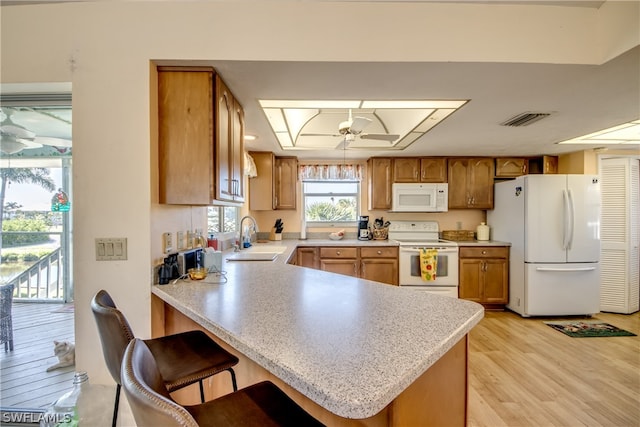 kitchen featuring kitchen peninsula, white appliances, ceiling fan, sink, and light wood-type flooring