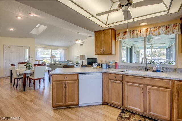 kitchen featuring ceiling fan, white dishwasher, sink, light wood-type flooring, and vaulted ceiling with skylight