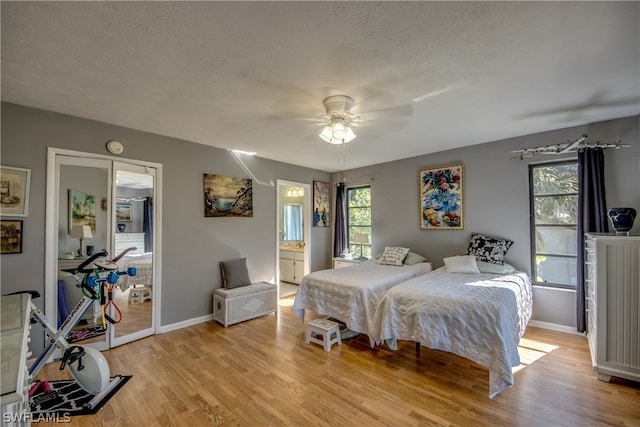 bedroom with light hardwood / wood-style floors, connected bathroom, ceiling fan, and a textured ceiling