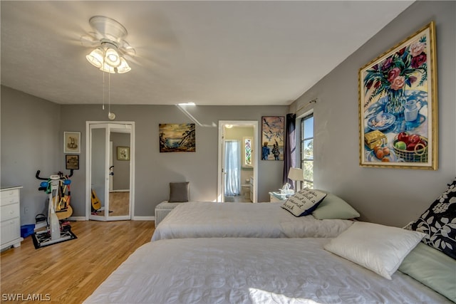 bedroom featuring ensuite bath, ceiling fan, and light wood-type flooring