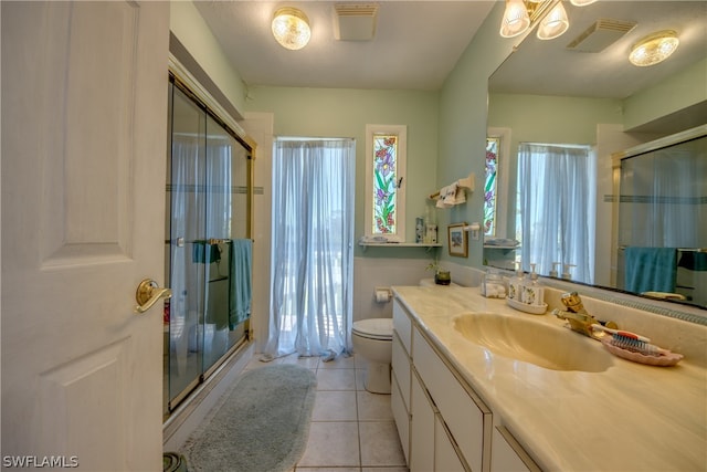 bathroom featuring tile floors, toilet, oversized vanity, and an enclosed shower