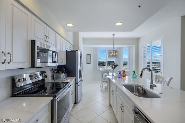 kitchen featuring pendant lighting, light tile floors, sink, appliances with stainless steel finishes, and white cabinetry