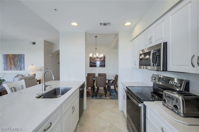 kitchen featuring sink, light tile floors, white cabinets, appliances with stainless steel finishes, and a notable chandelier