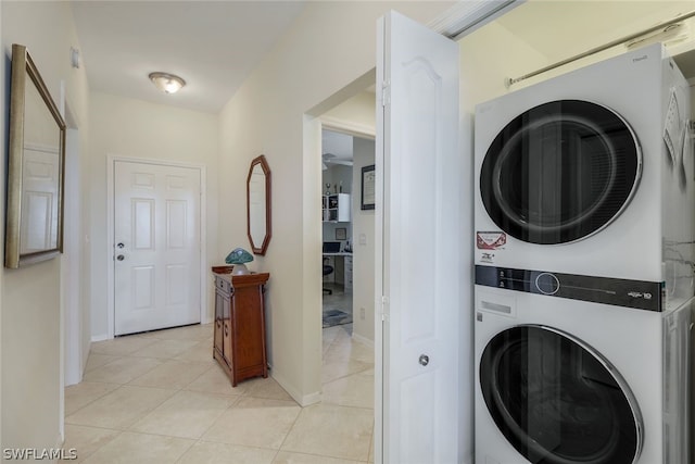 clothes washing area featuring stacked washer / drying machine and light tile flooring