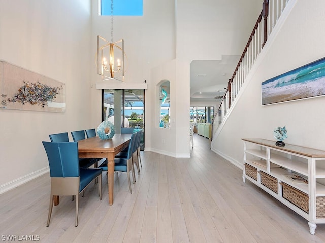 dining area with a chandelier, a high ceiling, and light hardwood / wood-style flooring