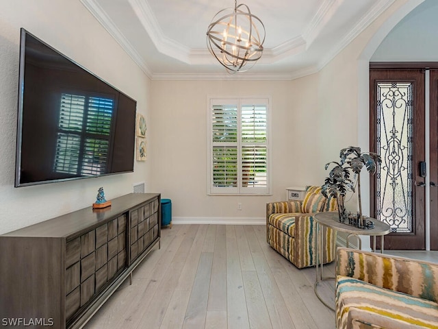 living area featuring light hardwood / wood-style flooring, crown molding, a notable chandelier, and a raised ceiling