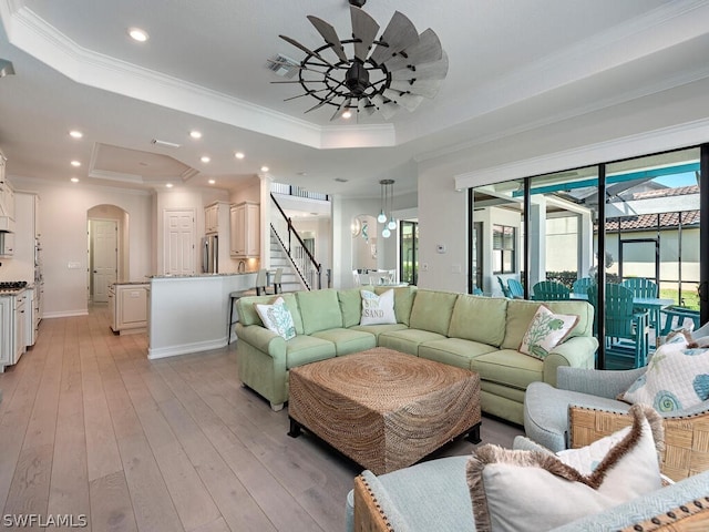 living room featuring ornamental molding, light hardwood / wood-style floors, ceiling fan, and a tray ceiling