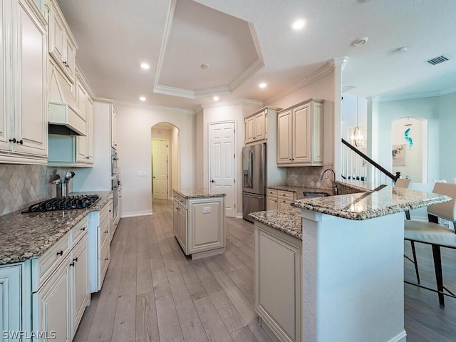 kitchen featuring backsplash, light hardwood / wood-style flooring, appliances with stainless steel finishes, and a tray ceiling