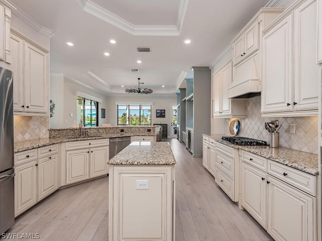 kitchen featuring tasteful backsplash, a center island, light hardwood / wood-style floors, and a tray ceiling