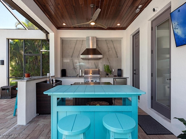 exterior space featuring tasteful backsplash, wall chimney range hood, ceiling fan, tile countertops, and wooden ceiling