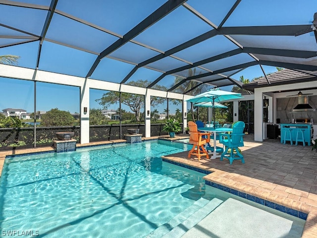 view of pool featuring pool water feature, glass enclosure, a patio, and ceiling fan