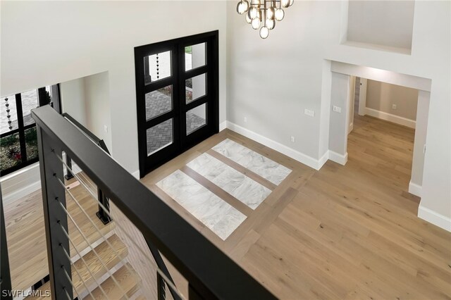 entryway with baseboards, a chandelier, wood finished floors, and french doors