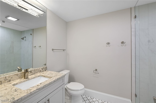 bathroom featuring vanity, a tile shower, and toilet