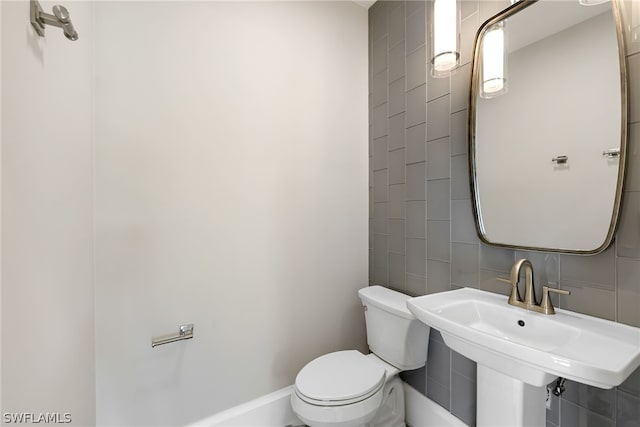 bathroom with toilet, sink, tile walls, and backsplash