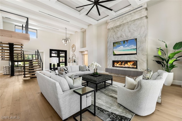 living room with a premium fireplace, light hardwood / wood-style floors, a high ceiling, and a wealth of natural light