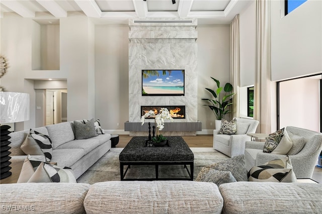 living room featuring a premium fireplace, a high ceiling, a wall mounted air conditioner, and light wood-type flooring