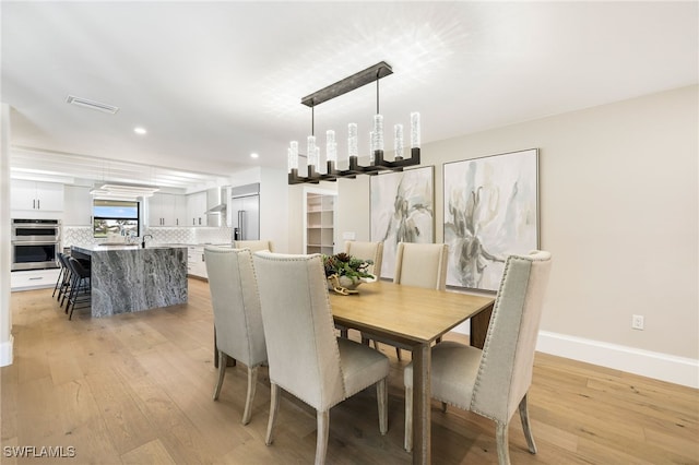 dining room with a chandelier and light hardwood / wood-style flooring