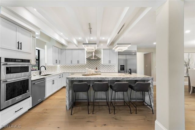 kitchen featuring beamed ceiling, stainless steel appliances, a center island, pendant lighting, and light hardwood / wood-style floors