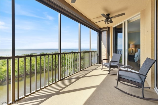 sunroom with a water view and ceiling fan