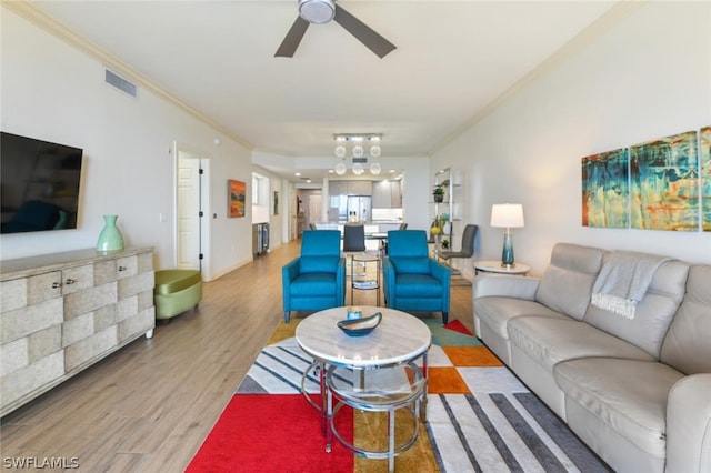 living room with ornamental molding, ceiling fan, and light wood-type flooring