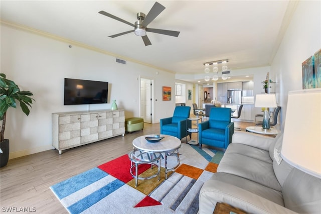 living room with ornamental molding, ceiling fan, and light hardwood / wood-style flooring