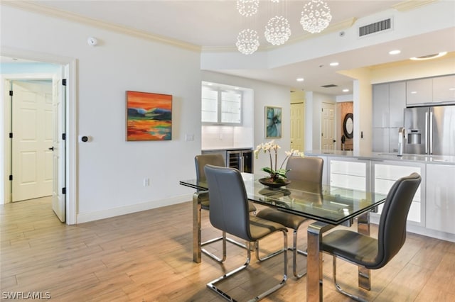 dining room featuring crown molding, an inviting chandelier, and light wood-type flooring