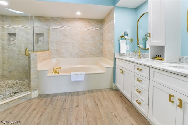 bathroom with double sink, shower with separate bathtub, and vanity with extensive cabinet space