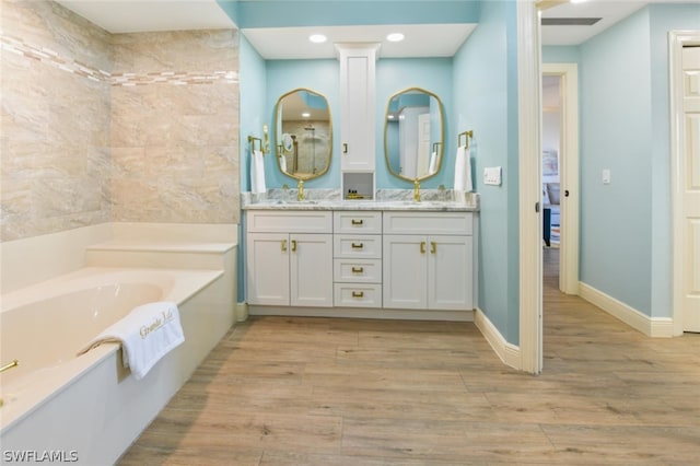 bathroom with dual vanity, a bathtub, and wood-type flooring