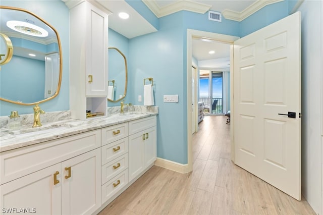 bathroom with crown molding, oversized vanity, hardwood / wood-style floors, and dual sinks